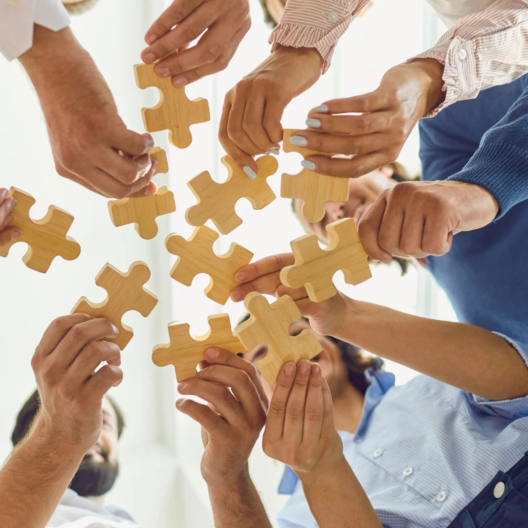 Tim ljudi spaja drvene puzzle delove – simbol saradnje i timskog rada u StandOut studiju